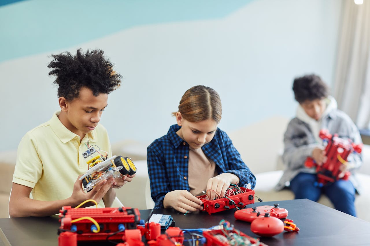 Three teenagers concentrating on robotics projects in a bright, indoor setting.